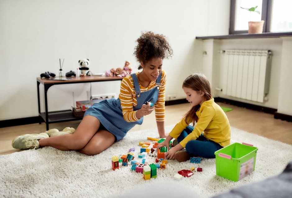 A babysitter and child playing with building blocks together