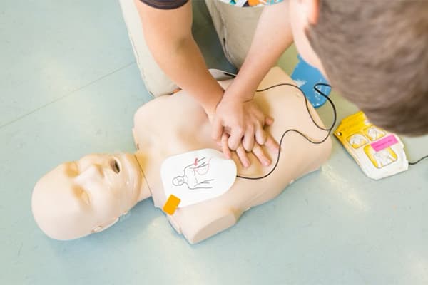 Practicing CPR on a manikin with AED training pads attached